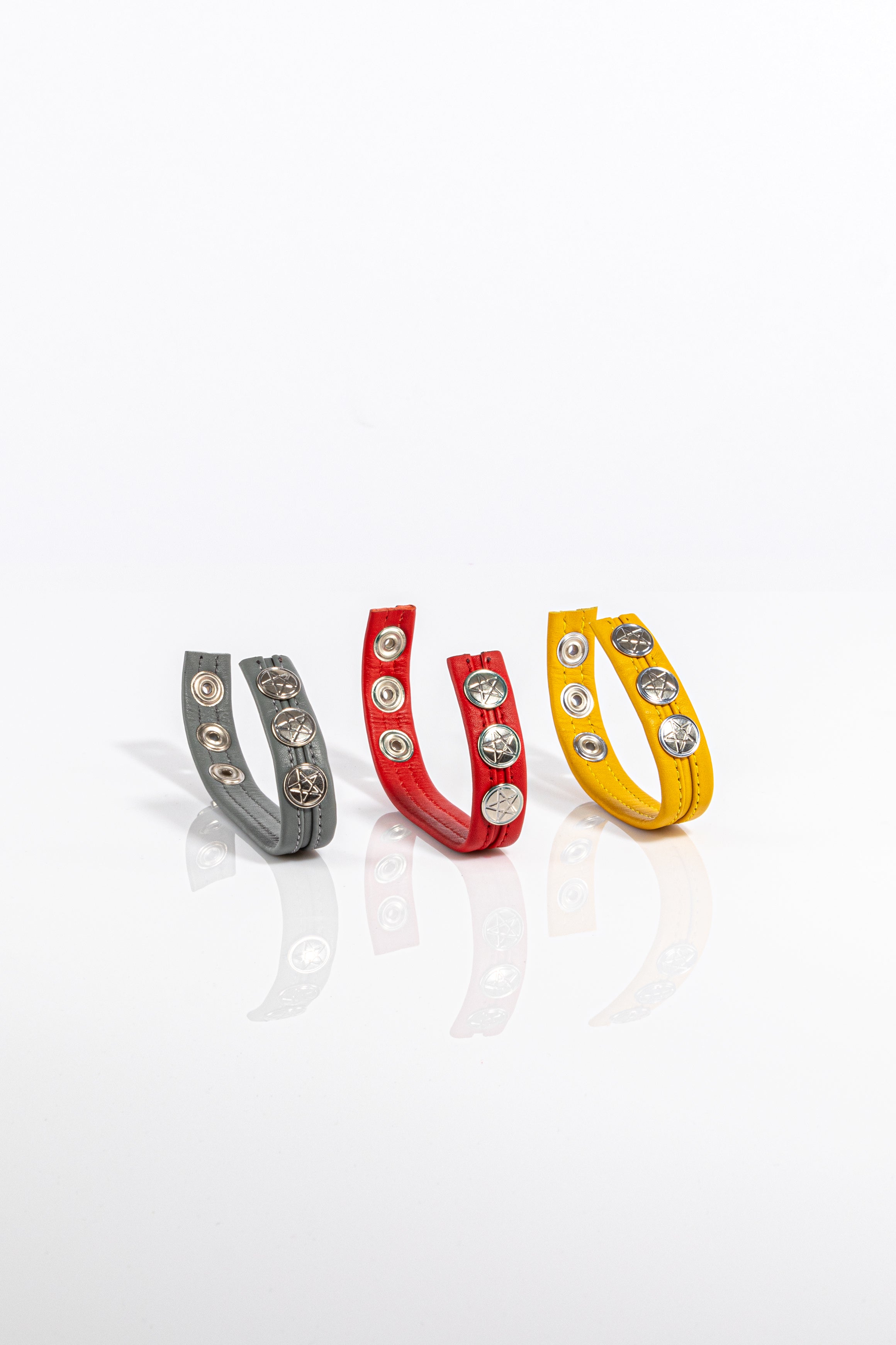 A product photo of three solid coloured leather cockrings.